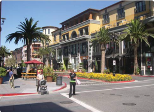 People Walking Along a Street with Palm Trees and Buildings