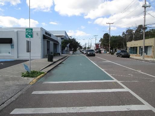 Photo of a green, paved bike trail along a street.