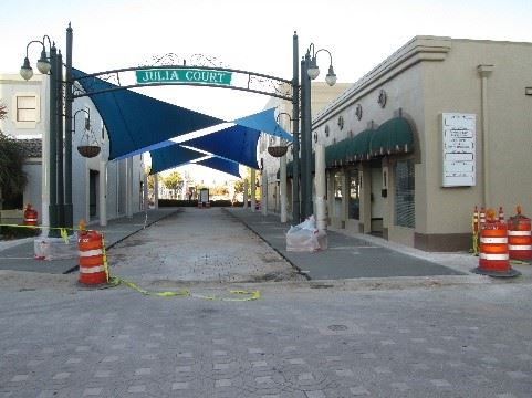 Photo showing new pavement in a courtyard between two buildings, with an arch sign in front.