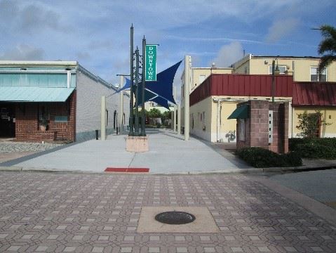 Photo showing a renovated courtyard with new concrete and shade sails.