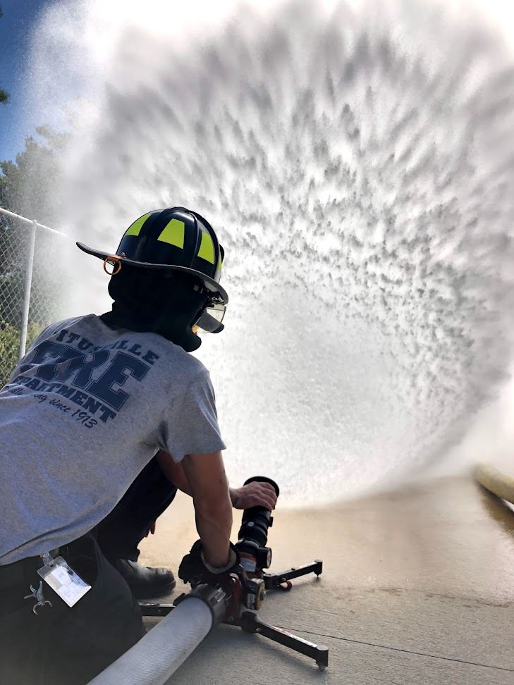 Firefighter spraying water from fire nozzle