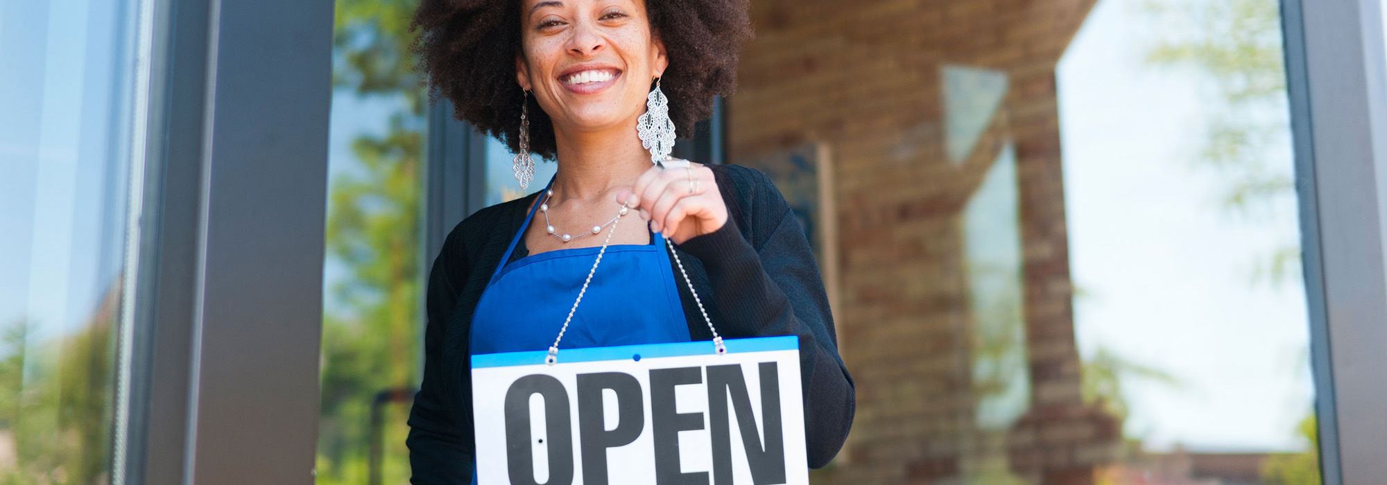 woman holding open sign